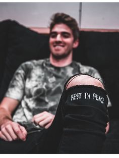 a man sitting on top of a couch with his arm wrapped around the leg that says rest in peace