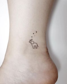 a small elephant tattoo on the side of a woman's foot with stars above it