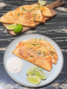 two slices of pizza on a plate with limes