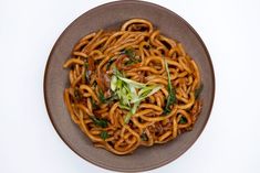 a brown plate with noodles and vegetables on it