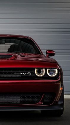 the front end of a red sports car parked in a parking lot next to a garage door