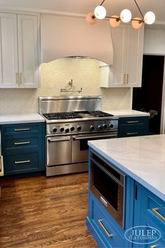 a kitchen with blue cabinets and stainless steel appliances, including an island stove top oven