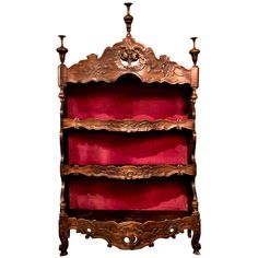 an ornately decorated shelf with candles on it's sides and red velvet lining the shelves