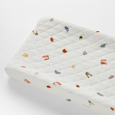 an image of a baby crib mattress that is made out of white fabric with colorful leaves on it