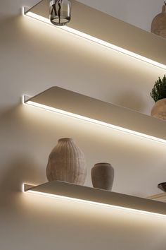 three white shelves with vases and lights on them