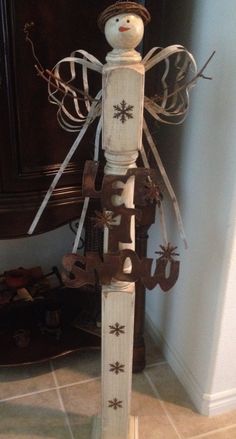 a snowman made out of wood and ribbon on top of a wooden stand in front of a mirror