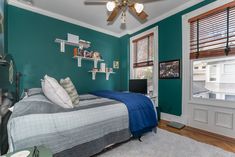 a bedroom with green walls and white trim on the ceiling is decorated in shades of teal