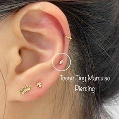 an ear piercing with three small green and white stones on the middle part of it