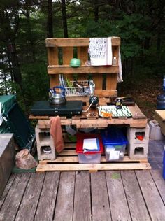 an outdoor kitchen made out of pallets on a wooden deck in the middle of a forest