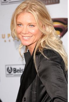 a woman with long blonde hair smiling at the camera and wearing a black blazer