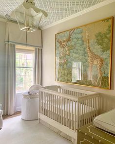 a baby's room with a giraffe painting on the wall and a crib