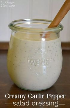 creamy garlic pepper salad dressing in a glass jar with a wooden spoon on the side