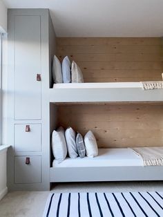 two bunk beds in a small room with wooden walls and white bedding on the bottom floor