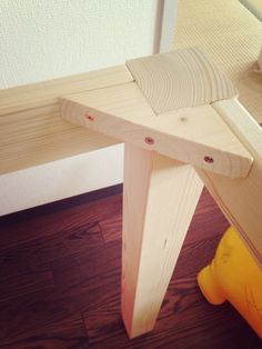 a wooden bench sitting on top of a hard wood floor next to a yellow object