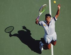 a man holding a tennis racquet on top of a tennis court with a ball in the air