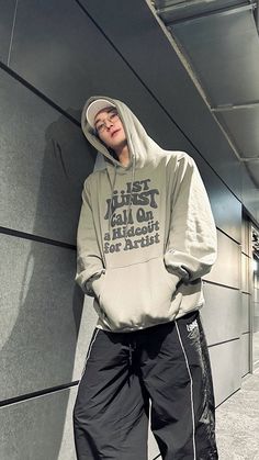 a person leaning against a wall wearing a hoodie