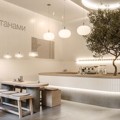 the interior of a restaurant with tables and stools next to a large olive tree