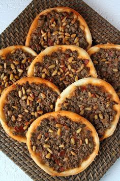 some kind of bread with meat and nuts on it sitting on a wicker platter