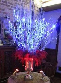 a vase filled with blue and red lights sitting on top of a table next to a brick wall