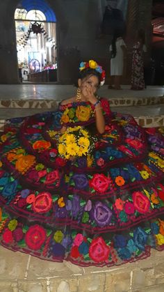 a woman laying on top of a colorful blanket in the middle of a floor covered in flowers