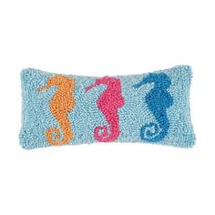 a blue pillow with three seahorses on the front and one is pink, orange, and blue