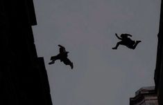 two people are flying in the air above some buildings