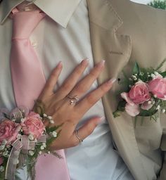 a close up of two people wearing wedding rings and holding flowers in their lapels