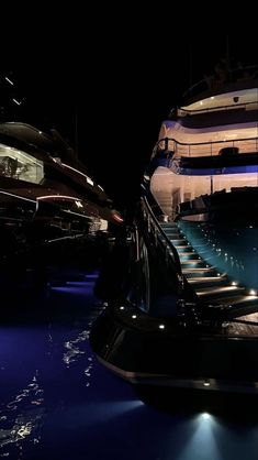 the stairs are lit up at night in front of a boat that is floating on water