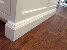 a kitchen with white cabinets and wood flooring on the side of the countertop