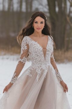 a woman in a wedding dress standing in the snow with her hands on her hips