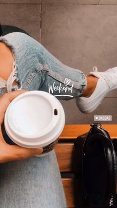 a woman sitting on a bench holding a coffee cup