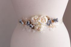 Gold blue  wedding sash Bridesmaid belt Color: gold /ivory/dusky blue with grey accent flowers  Materials:ivory lace , handmade  fabric flowers,blue paper flowers, beads,gold metal leaves, freshwater and faux pearls,wire,satin ribbon. Measurements: Applique approx L 7 inches, W 2.5 inches Applique attached to  ivory satin ribbon 25mm x 260 cm. MORE SASHES: https://www.etsy.com/uk/shop/WeddingJewelryOutlet?ref=seller-platform-mcnav§ion_id=26791561 WEDDING JEWELRY: https://www.etsy.com/uk/shop/WeddingJewelryOutlet?ref=seller-platform-mcnav§ion_id=26786154   MATCHING HEADPIECES: https://www.etsy.com/uk/shop/WeddingJewelryOutlet?ref=simple-shop-header-name&listing_id=724957245§ion_id=26785826 *Please NOTE colors may be slightly different than the monitor shows due to monitor differences. Some Elegant Bridal Belt With Handmade Flowers For Weddings, Elegant Blue Bridal Belt For Wedding, Elegant Bridal Belt With Flower Decoration For Wedding, Elegant Blue Sashes For Wedding, Bridesmaid Belt, Wedding Dress Sash, Dusky Blue, Dress Sash, Wedding Sash Belt