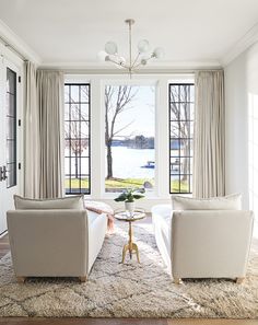 a living room with two couches and a coffee table in front of large windows