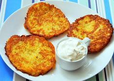 three pancakes on a white plate with a small bowl of whipped cream next to it