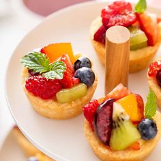 small fruit tarts on a white plate with wooden utensils in the middle