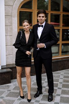 a man and woman standing next to each other in front of a building with large windows