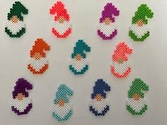 cross stitch gnomes are arranged on a white surface, each with different colors and sizes