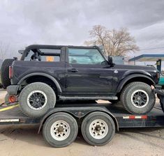 a flatbed trailer with a black truck on it