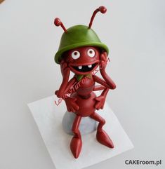 a red toy sitting on top of a white piece of paper with eyes and legs