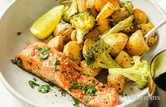 a white plate topped with salmon, potatoes and broccoli