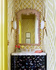 a bathroom with yellow walls and a butterfly patterned cabinet in the corner next to a mirror