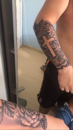 a man with a cross tattoo on his arm next to another person's leg