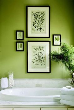 a bathroom with green walls and pictures on the wall above the jacuzzi tub