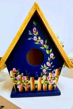 a blue birdhouse with flowers painted on it's side and candles in the bottom