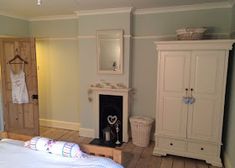 a bedroom with a bed, dresser and mirror in it's corner next to a fireplace