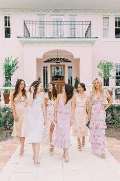 a group of women standing in front of a pink house