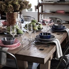 a wooden table topped with plates and glasses