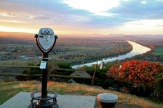 a coin operated parking meter on top of a hill overlooking a river and hills in the distance