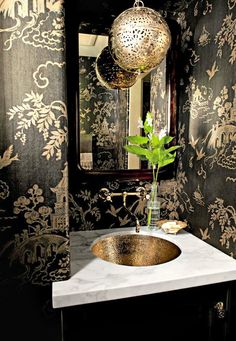 a bathroom with a sink, mirror and wallpapered walls in black and gold