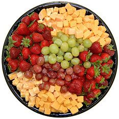 a platter of cheese, grapes and strawberries on a black plate with white background